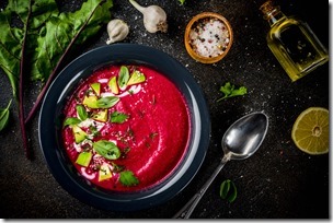 Vegan food, summer cold Beetroot gazpacho soup with lemon, avocado and fresh herbs copy space top view