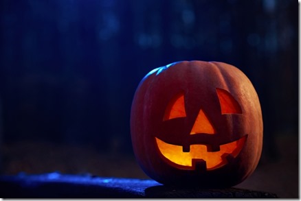 Horizontal shot of a jack head Halloween lantern pumpkin in the darkness of a mysterious autumn forest candle burning inside copyspace. 