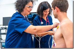 Cardiologist placing electrodes on a patient for a stress test