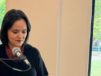Mujer periodista trabajando en una oficina frente a una computadora analizando noticias