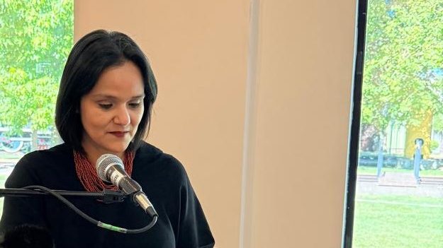 Mujer periodista trabajando en una oficina frente a una computadora analizando noticias