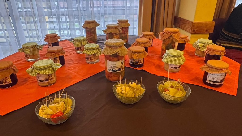 Mujeres rurales de Victoria participando en taller de conservas y encurtidos junto a sus productos elaborados
