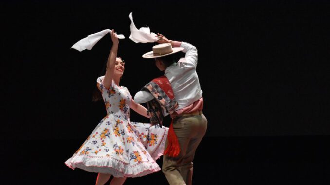 Pareja bailando cueca chilena en un entorno cultural universitario