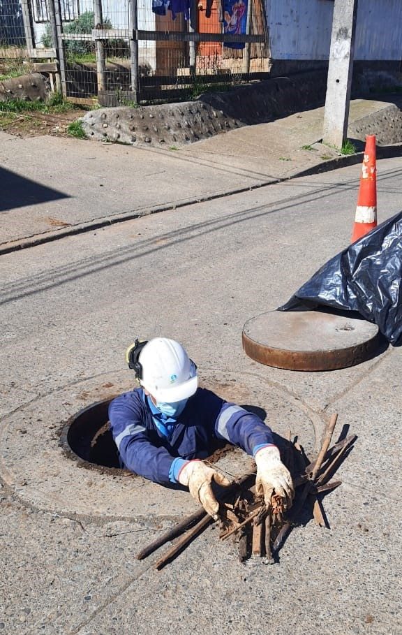 Personal técnico inspeccionando una cámara de alcantarillado obstruida por residuos de construcción