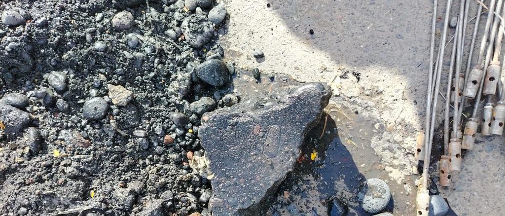 Personal técnico inspeccionando una cámara de alcantarillado obstruida por residuos de construcción