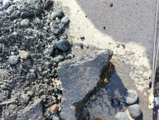 Personal técnico inspeccionando una cámara de alcantarillado obstruida por residuos de construcción