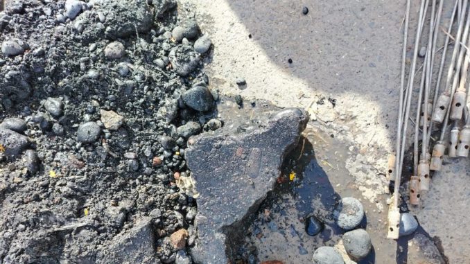 Personal técnico inspeccionando una cámara de alcantarillado obstruida por residuos de construcción