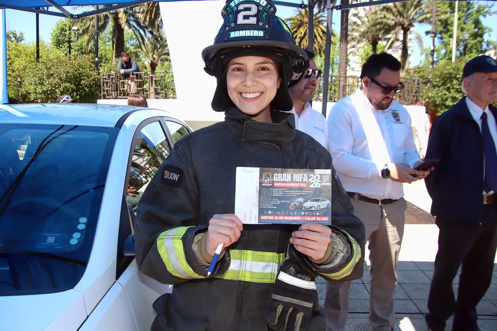 Voluntarios de Bomberos de Temuco presentando la Gran Rifa Monumental 2026 con un auto y moto en exhibición.